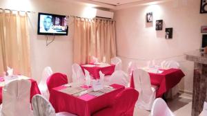科纳克里Hotel du Golfe de Guinee的一间设有红色桌子和白色椅子及电视的房间