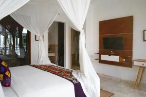乌布Sabana Ubud的一间卧室配有带白色窗帘的床和电视。