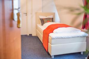 弗伦斯堡诺德格酒店的小卧室配有带橙色毯子的床