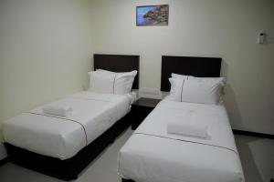 北赖DCozy Hotel的配有白色床单的酒店客房内的两张床