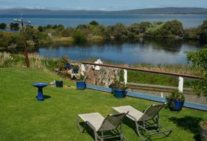 奥尔巴尼Kinsellas Water Views的湖畔草坪上两把椅子和一张桌子