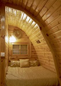 CorredouraThe Gold Pod, relax and enjoy on a Glamping house的木制客房内的一间卧室,配有一张床