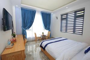 大叻Luan'S Villa的一间卧室配有一张床、一张书桌和一台电视