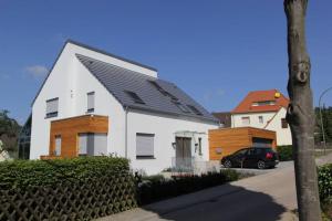奥斯纳布吕克Stilvolles Studio的白色的房子,有黑色的屋顶和汽车