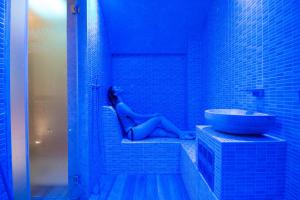 阿韦特拉纳Masseria Grottella的蓝色浴室里的女人,浴室里设有水槽