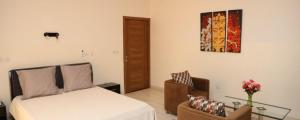 巴马科Villa Mariam的一间卧室配有一张床、一把椅子和一张桌子