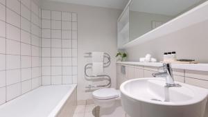 奥克兰Auckland Harbour Suites的白色的浴室设有水槽和卫生间。
