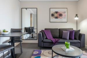 奥克兰Avani Metropolis Auckland Residences的客厅配有沙发和桌子