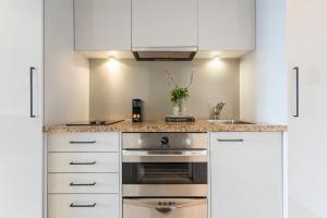 奥克兰Avani Metropolis Auckland Residences的厨房配有白色橱柜和炉灶。