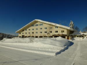 东川町K's House Hokkaido - Asahidake Onsen Hostel的一座被雪覆盖的建筑,靠近公路