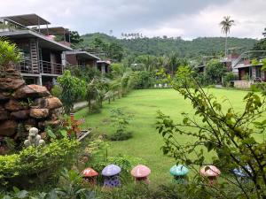 湄南海滩Baan Boom Boxes Eco Friendly Resort的房子旁边的草地上带雨伞的院子