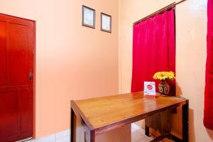 日惹SUPER OYO 1788 House 24的配有木桌和红色窗帘的房间