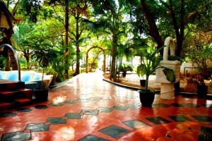 贾夫纳Tilko City Hotel Jaffna的一个带树木和红色瓷砖地板的庭院