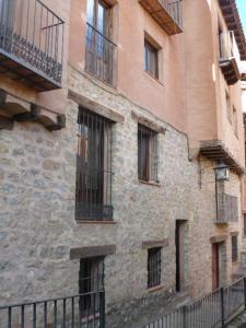 阿尔巴拉辛CASA CENTRO ALBARRACIN的旧砖砌的建筑,设有窗户和栅栏