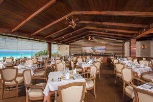 坎昆Iberostar Selection Cancun的餐厅设有白色的桌椅和一扇窗户