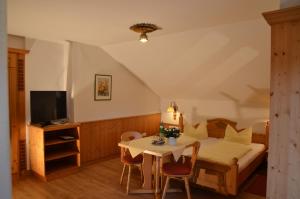 加尔米施-帕滕基兴玛丽亚宾馆的一间卧室配有一张床、一张桌子和一台电视。