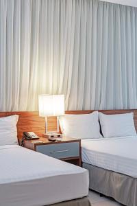 波多韦柳Slaviero Porto Velho的酒店客房设有两张床和一张带台灯的桌子。