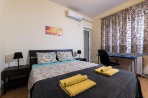 斯巴达Alexander Apartments Airport的一间卧室配有一张带两张黄色毛巾的床