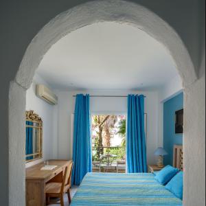 卡马利阿拉斯汉姆海滩酒店的一间卧室配有蓝色窗帘、一张床和一张书桌