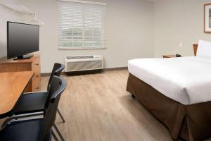 麦迪逊Woodspring Suites Huntsville/ Madison的一间卧室配有一张床和一张书桌及电视
