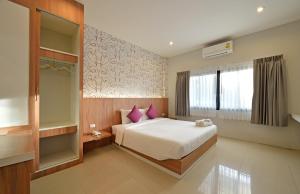甲米镇台拉达精品酒店的一间卧室配有一张带紫色枕头的床和窗户。