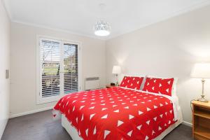 芒特甘比尔City One Apartment的白色的窗户客房内的一张红色的床