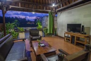 乌布Bali Spirit Hotel and Spa, Ubud的一间带电视和桌子的客厅