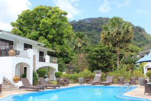博瓦隆森普拉帕蒂斯度假酒店的一座带椅子和树木的别墅前的游泳池