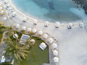 莫拉托斯Minos Imperial Luxury Beach Resort & Spa Milatos的享有海滩上方的白色遮阳伞和棕榈树美景