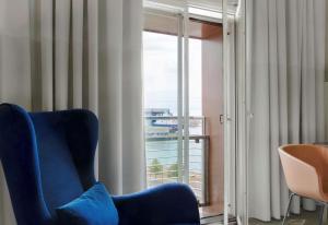 赫尔辛基赫尔辛基丽笙海滨酒店的窗户客房内的蓝色椅子