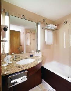 阿斯隆阿斯隆丽笙酒店的浴室配有水槽、浴缸和浴缸。