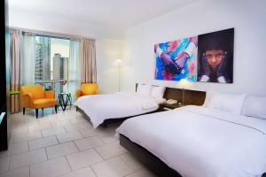 巴拿马城Decapolis Hotel Panama City的酒店客房设有两张床,墙上挂着一幅大画。