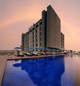 新德里新德里帕池豪尔丽笙酒店的酒店设有一个大型游泳池,配有椅子和遮阳伞