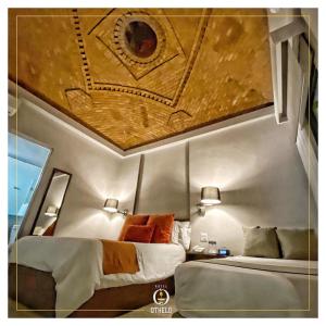莱昂Othelo Boutique Hotel Mexico的一间带两张床的卧室,位于一个天花板的房间