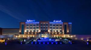 索哈尔Radisson Blu Hotel & Resort, Sohar的建筑前有蓝色灯光的酒店