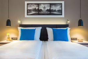 曼海姆曼海姆丽笙酒店的一间卧室配有两张带蓝白色枕头的床