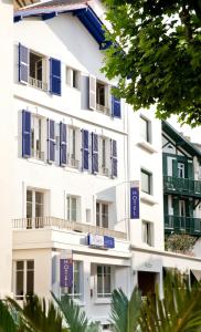 比亚里茨萨菲尔酒店的公寓大楼拥有蓝色百叶窗和树木