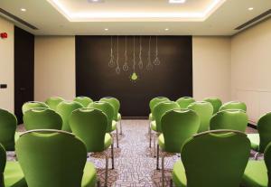 伊兹密尔伊兹密尔丽柏酒店的一间会议室,配有绿色椅子和屏幕