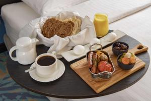 奥朱贝尔Park Inn by Radisson Jubail Industrial City的床上的早餐食品和咖啡托盘