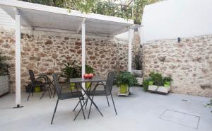 雅典A litte Taste of Home Guest House的一个带桌椅和砖墙的庭院