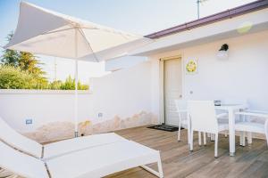 普蒂尼亚诺Una Perla Nel Verde的白色的庭院配有桌椅和遮阳伞。