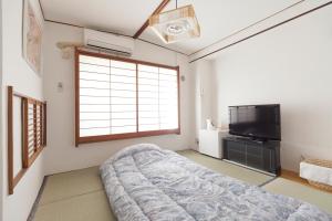 东京新大久保石亭酒店的一间卧室配有一张床和一台平面电视