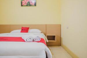 LampungRedDoorz near RS Imanuel Lampung的一间卧室配有红色和白色毛巾。