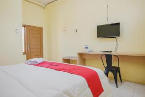 LampungRedDoorz near RS Imanuel Lampung的一间卧室配有一张床、一张书桌和一台电视
