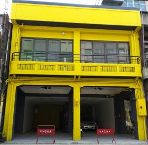 嘉义市客旅家青年旅館 Travelers Plus的前面有两把红色椅子的黄色建筑