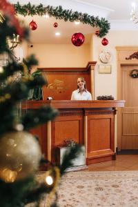 卡罗维发利全境温泉酒店的站在一个拥有圣诞装饰的房间的柜台后面的人