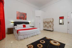 GeutieueRedDoorz Syariah near Museum Tsunami Aceh 2的一间卧室配有一张带红色和白色棉被的床