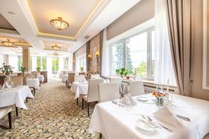 巴登韦勒卡塔琳娜公园水疗酒店的餐厅设有白色的桌椅和窗户。