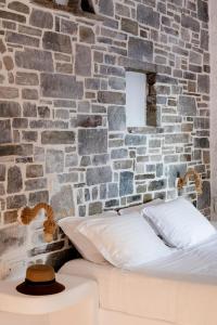 纳乌萨Zefi Hotel & Suites的一间卧室设有砖墙和一张带帽子的床