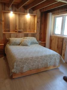 St-Pierre-de-l'Île-d'OrléansAu Vieux Foyer的卧室配有一张床铺,位于带木墙的房间内